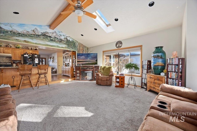 living room with light carpet, ceiling fan, and vaulted ceiling with skylight