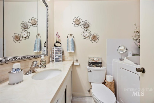 bathroom with vanity, a bathtub, washer / dryer, and toilet