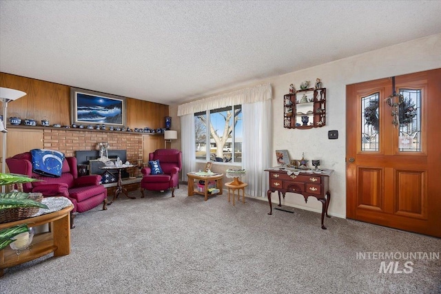 living area featuring wooden walls, carpet floors, and a textured ceiling