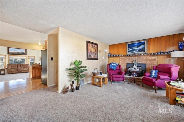 living room featuring light carpet, a textured ceiling, and wood walls