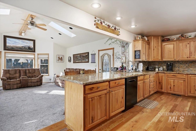 kitchen featuring light stone countertops, black dishwasher, sink, and kitchen peninsula