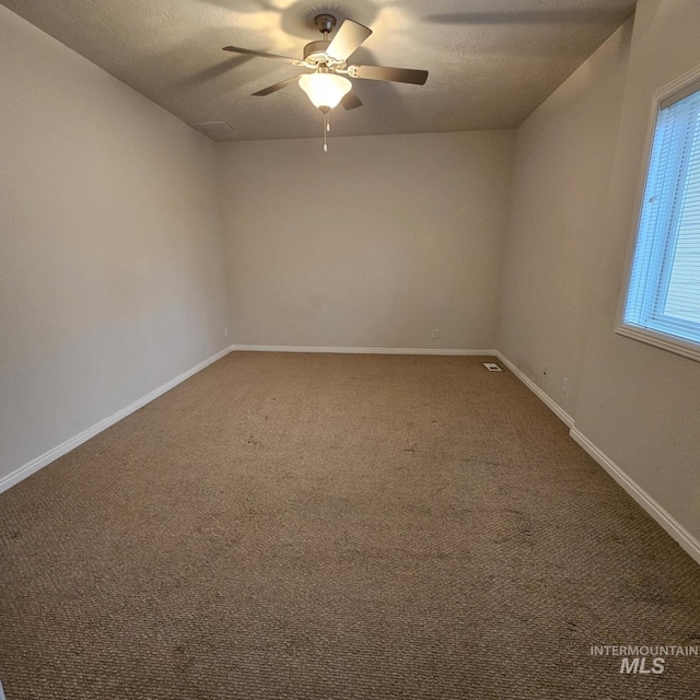 carpeted spare room featuring a textured ceiling and ceiling fan