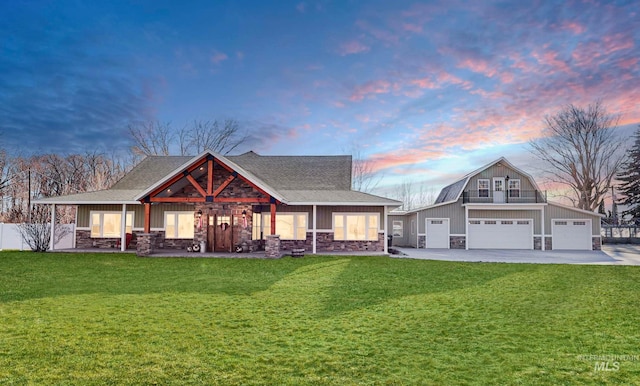 view of front of property with a garage, stone siding, a front lawn, and an outbuilding