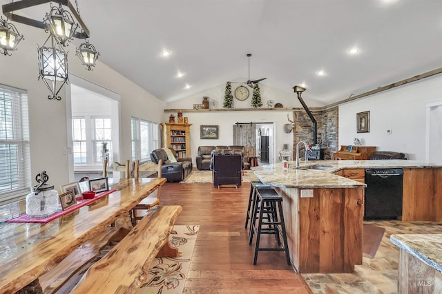 kitchen featuring high vaulted ceiling, light wood-style flooring, a sink, black dishwasher, and open floor plan