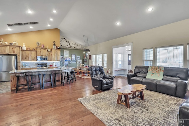 living room featuring light wood-style floors, recessed lighting, visible vents, and high vaulted ceiling