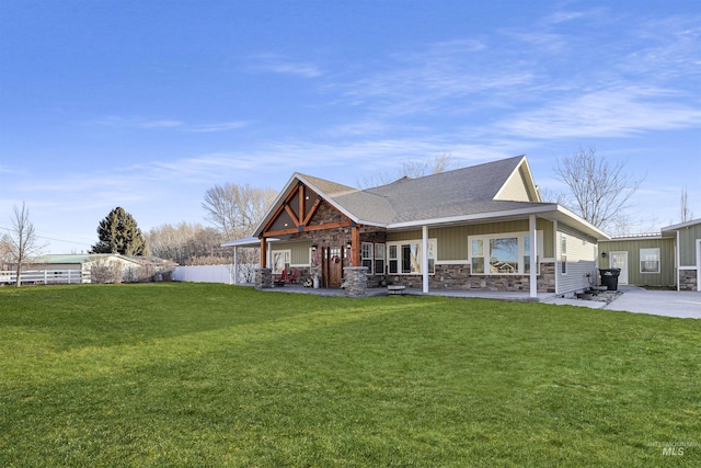 rear view of property with board and batten siding, stone siding, roof with shingles, and a yard