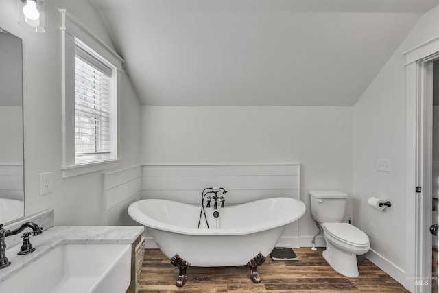 full bath featuring toilet, wood finished floors, a sink, vaulted ceiling, and a soaking tub