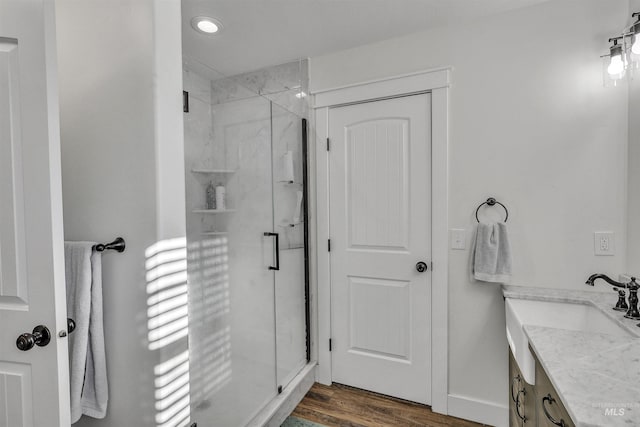 full bath featuring a shower stall, baseboards, wood finished floors, and vanity