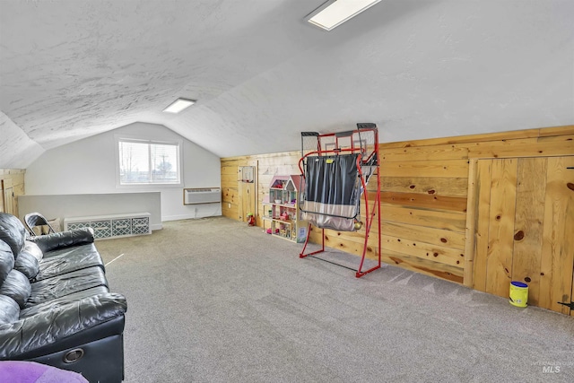 interior space featuring carpet flooring, vaulted ceiling, wooden walls, a textured ceiling, and a wall mounted air conditioner