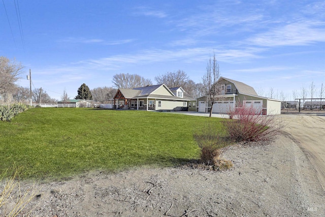 view of front of property featuring driveway, fence, an outbuilding, and a front yard