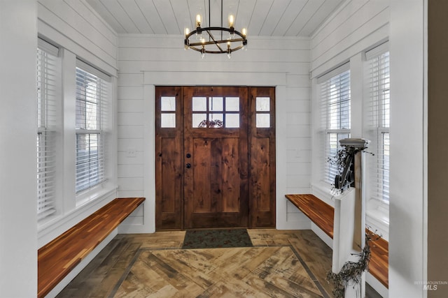 entryway with wood ceiling, a notable chandelier, wooden walls, and wood finished floors