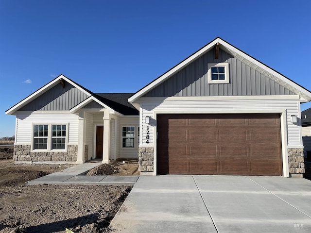 modern inspired farmhouse featuring a garage, stone siding, board and batten siding, and concrete driveway