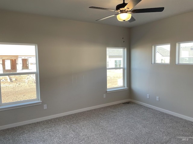 carpeted empty room featuring ceiling fan and baseboards