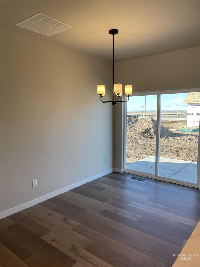 empty room with visible vents, dark wood-type flooring, and a notable chandelier