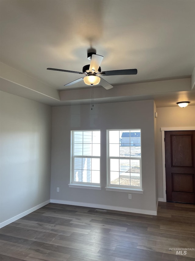 empty room featuring a ceiling fan, baseboards, and wood finished floors