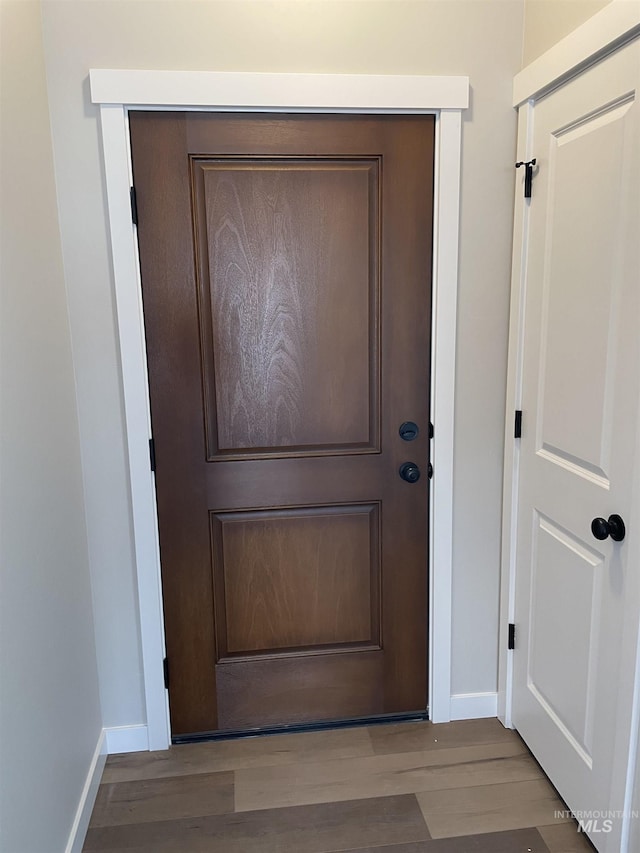 doorway featuring baseboards and wood finished floors