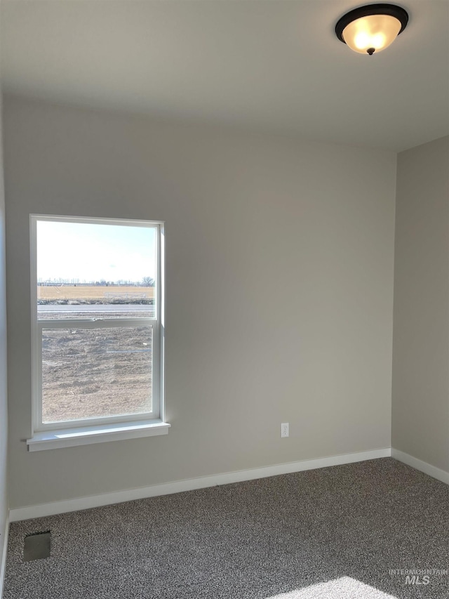 carpeted spare room featuring visible vents and baseboards