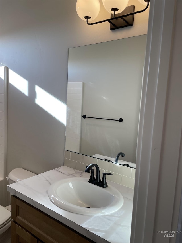 bathroom with decorative backsplash, vanity, and toilet