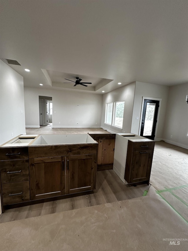 941 Gregory Way, Twin Falls, ID 83301 - kitchen with light wood-style flooring, a tray ceiling, dark brown cabinetry, open floor plan, and ceiling fan