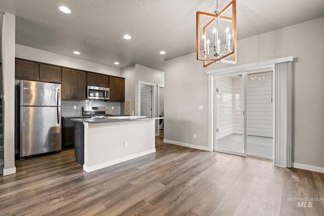 kitchen featuring dark brown cabinetry, baseboards, dark wood-style floors, stainless steel appliances, and backsplash