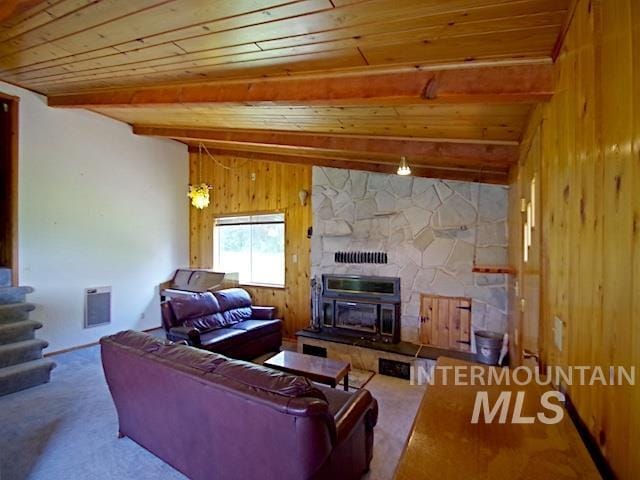 living room with a fireplace, a wood stove, wood ceiling, carpet flooring, and vaulted ceiling with beams