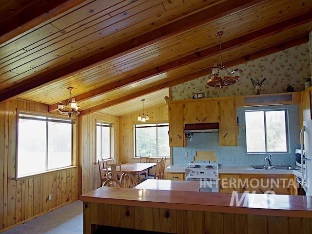 kitchen featuring a wealth of natural light, hanging light fixtures, an inviting chandelier, and lofted ceiling with beams