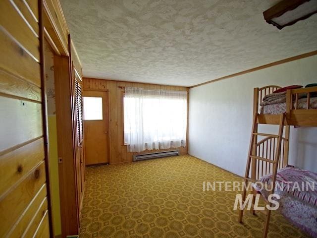 interior space with a baseboard heating unit, crown molding, a textured ceiling, and wood walls