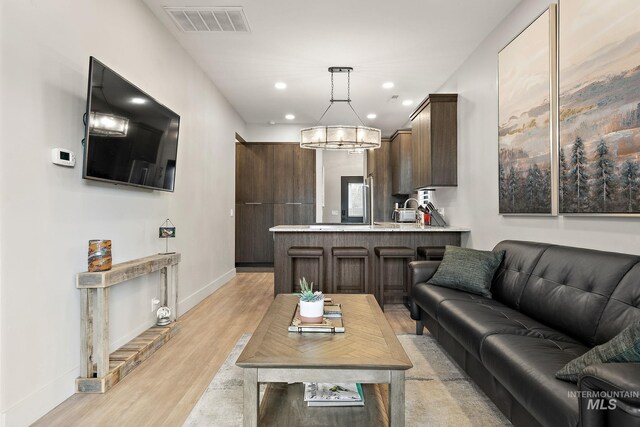 living area with recessed lighting, light wood-type flooring, visible vents, and baseboards