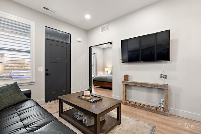 living room with light wood-type flooring, visible vents, baseboards, and recessed lighting