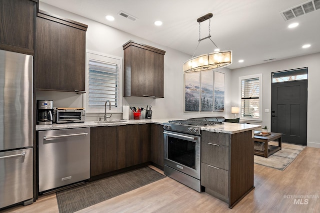 kitchen featuring stainless steel appliances, dark brown cabinets, a sink, and visible vents