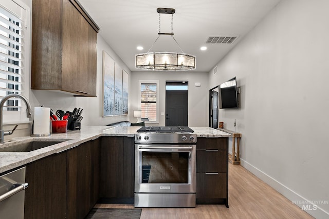 kitchen with stainless steel appliances, a sink, visible vents, and dark brown cabinetry