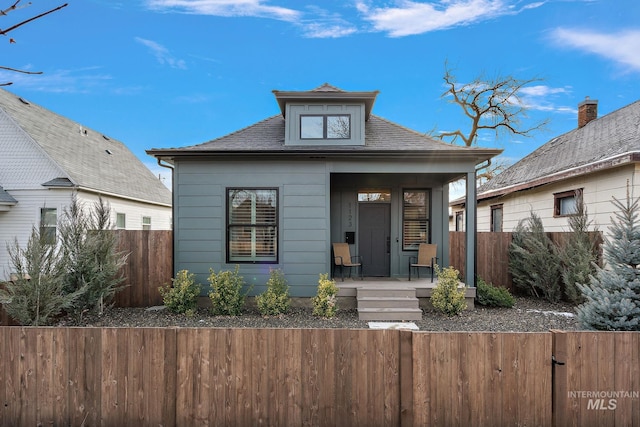 view of front of property featuring a porch, roof with shingles, and fence private yard