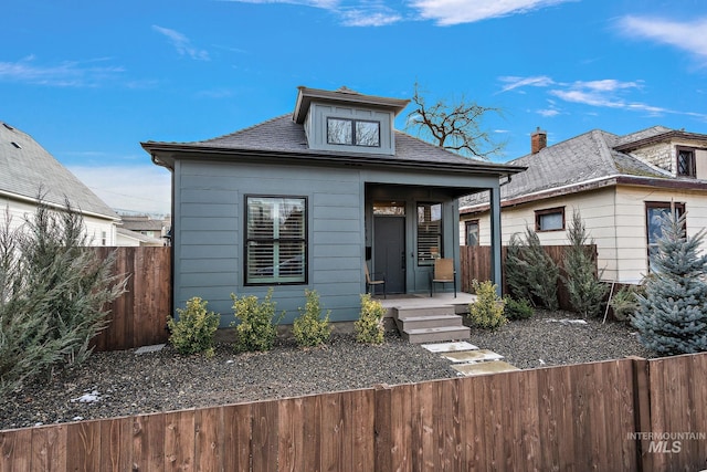 bungalow-style home with fence private yard, a shingled roof, and a porch