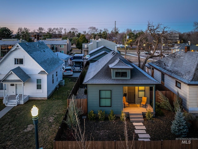 view of front of home featuring a porch, a front yard, fence, and a residential view