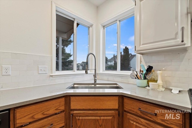 kitchen featuring backsplash, light countertops, brown cabinets, and a sink