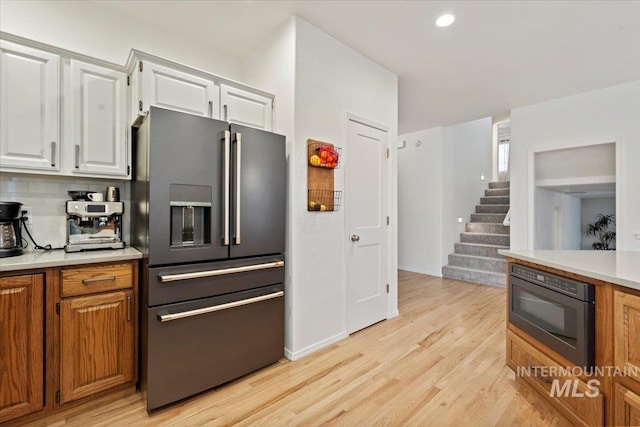 kitchen with high end refrigerator, white cabinets, light countertops, and light wood-style floors