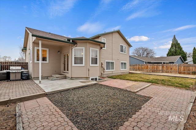 rear view of house with entry steps, a patio area, a lawn, and fence private yard