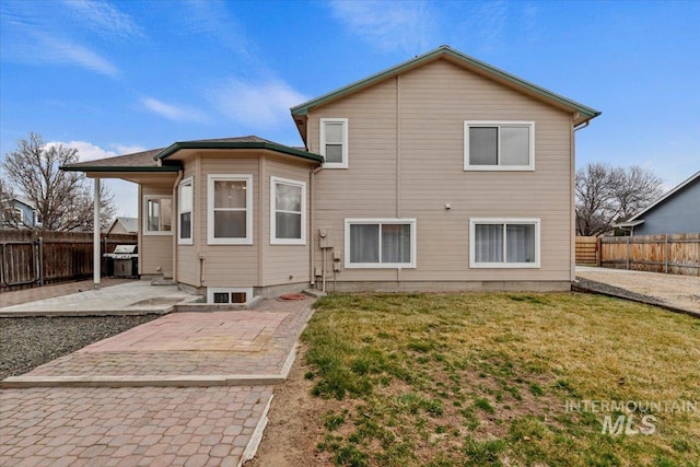 rear view of house featuring a patio, a lawn, and a fenced backyard