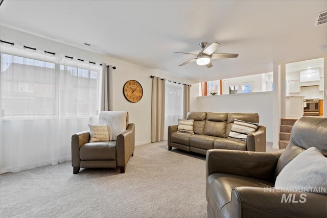 living room featuring carpet flooring, visible vents, baseboards, and a ceiling fan