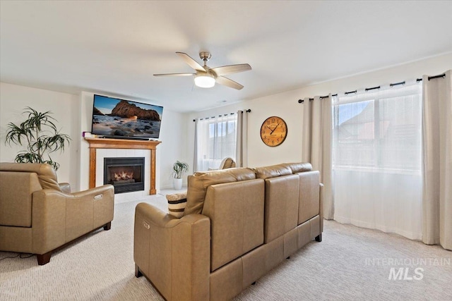 living area featuring light colored carpet, ceiling fan, and a tile fireplace