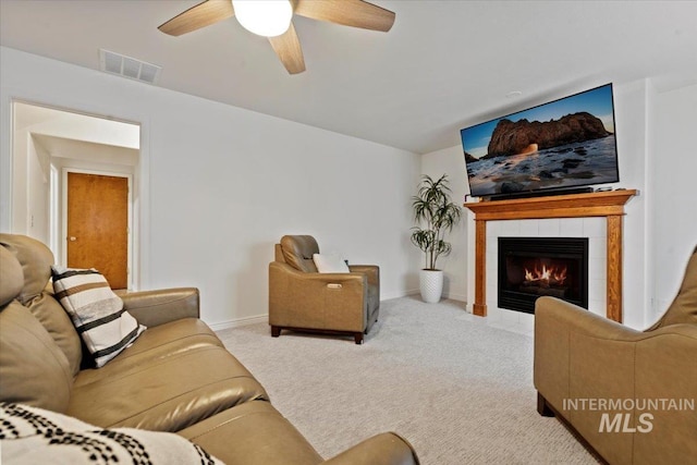 living area featuring visible vents, a tiled fireplace, carpet flooring, baseboards, and ceiling fan