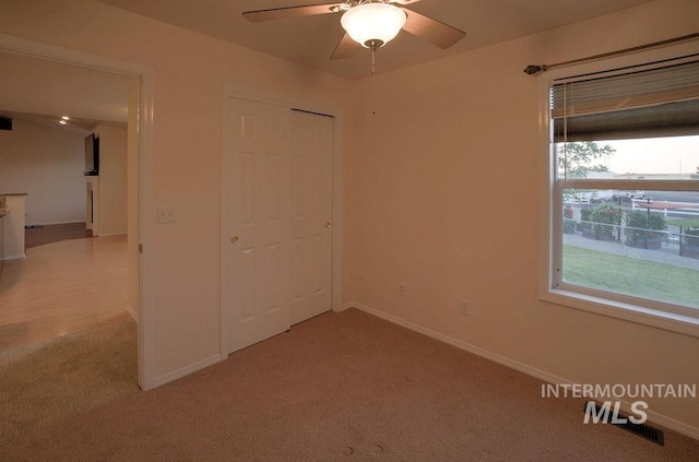 carpeted spare room featuring ceiling fan