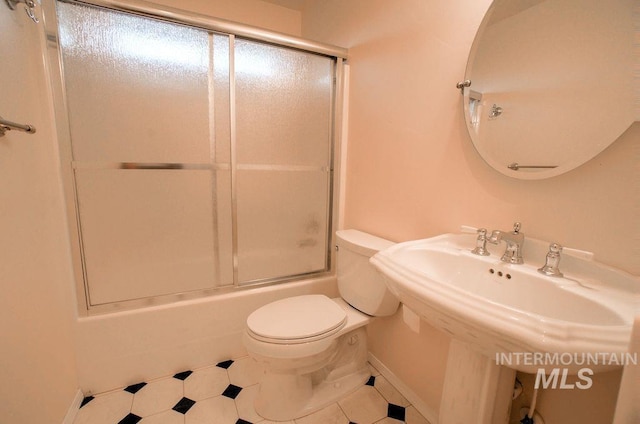 bathroom with tile patterned floors, toilet, and combined bath / shower with glass door