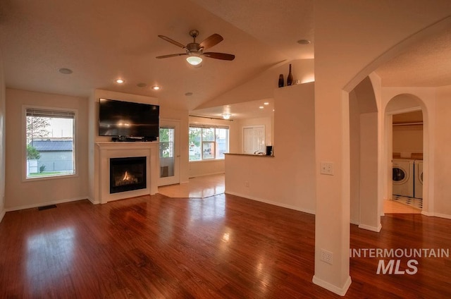 unfurnished living room featuring hardwood / wood-style floors, independent washer and dryer, lofted ceiling, and ceiling fan