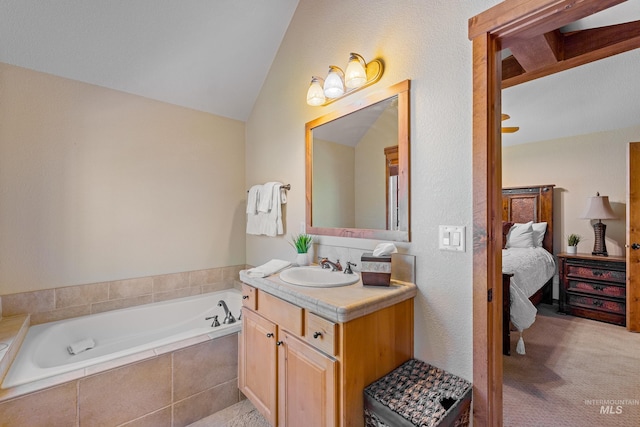 bathroom with vanity, a relaxing tiled tub, and vaulted ceiling