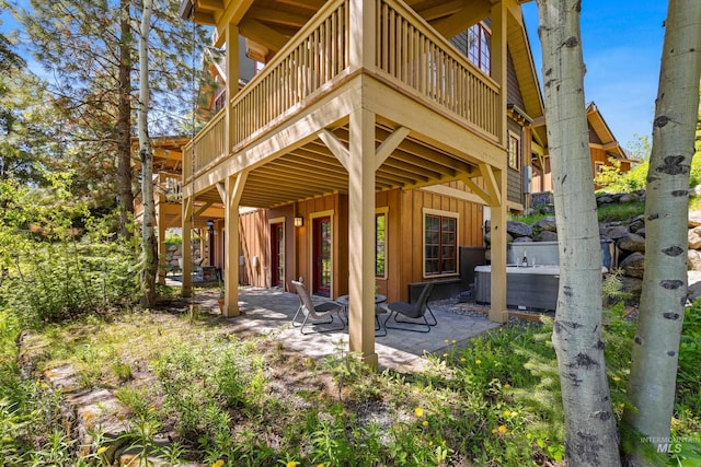 back of house featuring a patio, a hot tub, and a deck