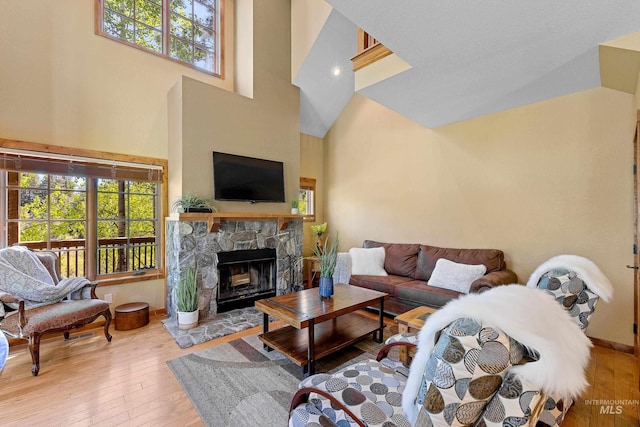 living room featuring a fireplace, a high ceiling, and light hardwood / wood-style flooring