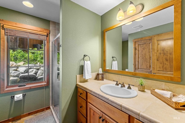 bathroom featuring vanity and a shower with door