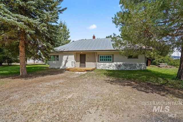 view of front of house with a chimney, metal roof, and a front yard