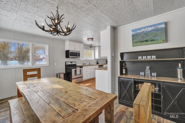 dining space featuring an inviting chandelier, a dry bar, and light wood finished floors